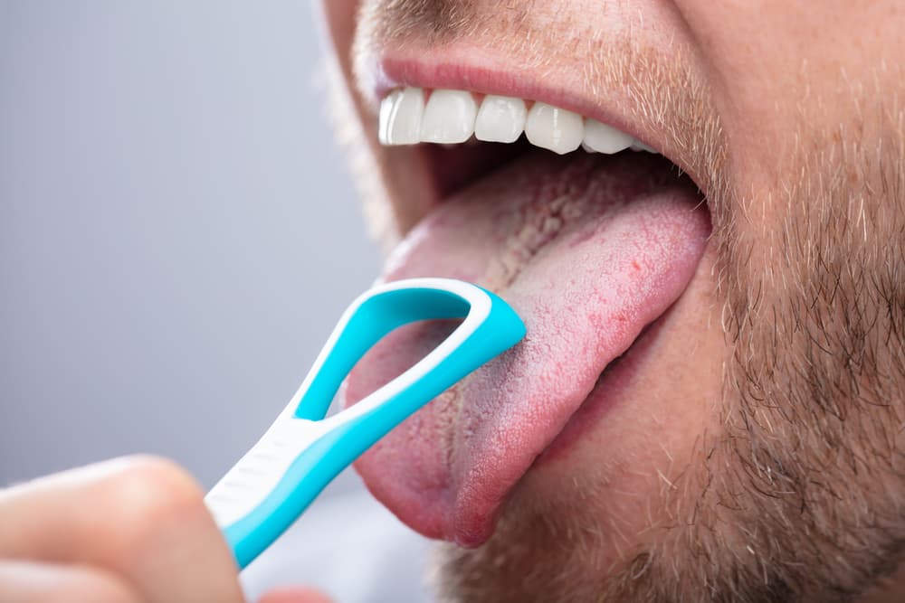 man cleaning his tongue with scraper