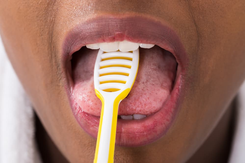 women cleaning tongue with scraper